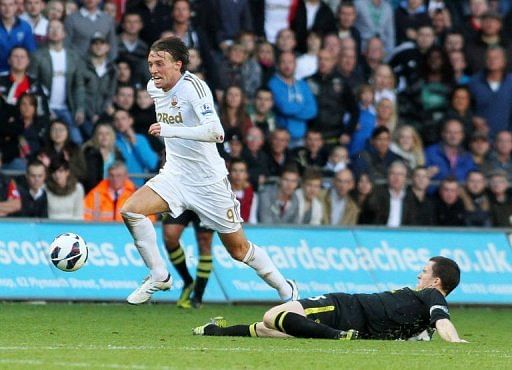 Michu (L) of Swansea avoids a tackle by Wigan's Gary Caldwell